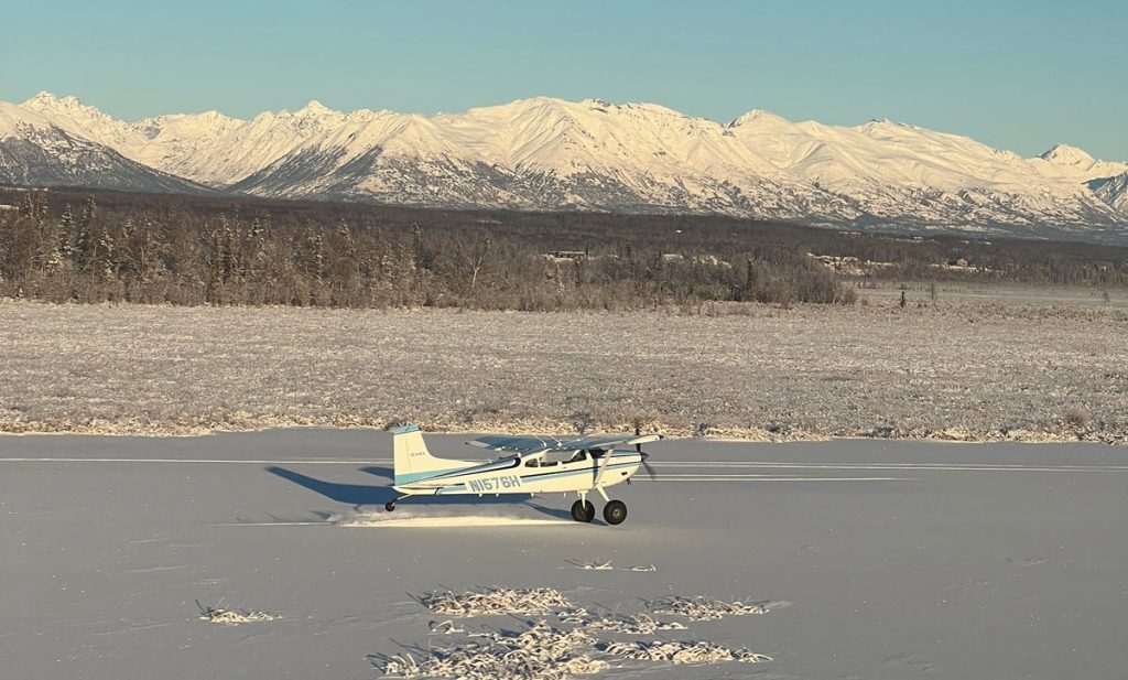 Cessna 185 on snow with mountains in the background