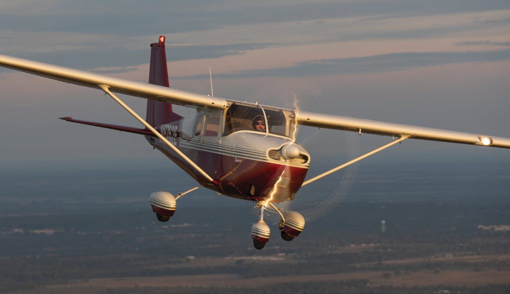 white and red cessna skylark in flight