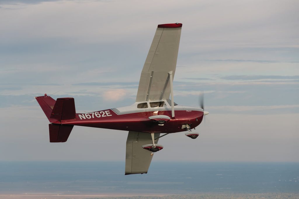 belly view of red and white cessna skylark in flight
